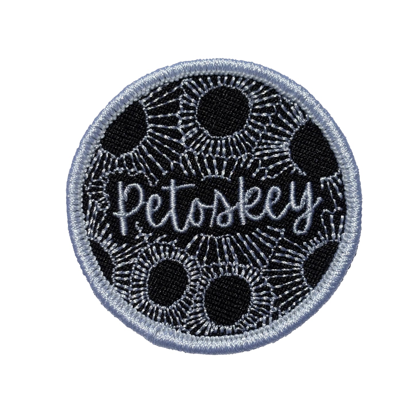 Circular patch with 'Petoskey' text on a Black and white Petoskey stone pattern background
