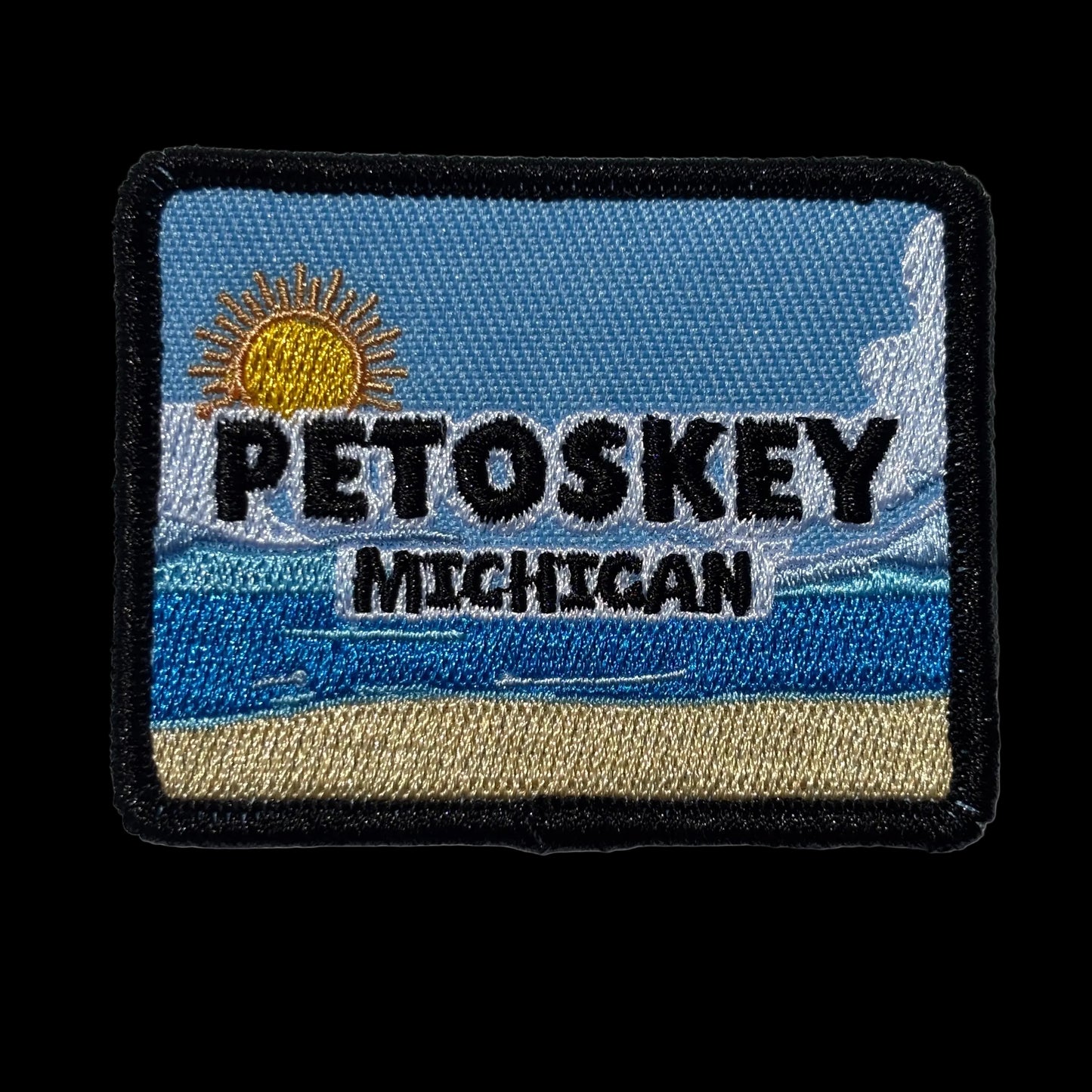 Patch with 'Petoskey Michigan' text on a blue and beige beach scene background