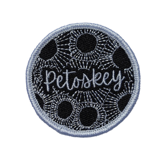 Circular patch with 'Petoskey' text on a Black and white Petoskey stone pattern background