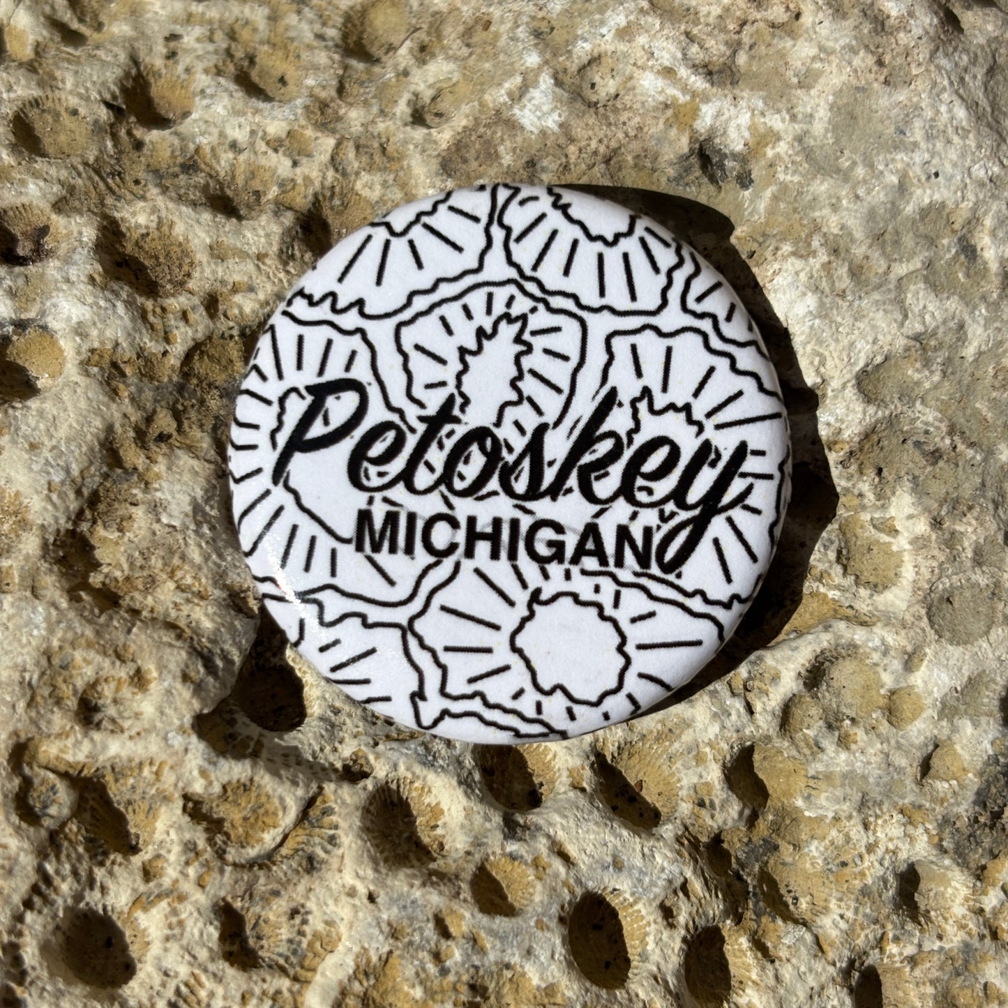 Round button with 'Petoskey Michigan' text on a textured stone surface