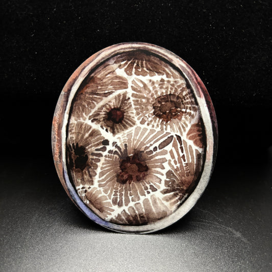 Round oval sticker with a watercolor petoskey stone pattern on a black background