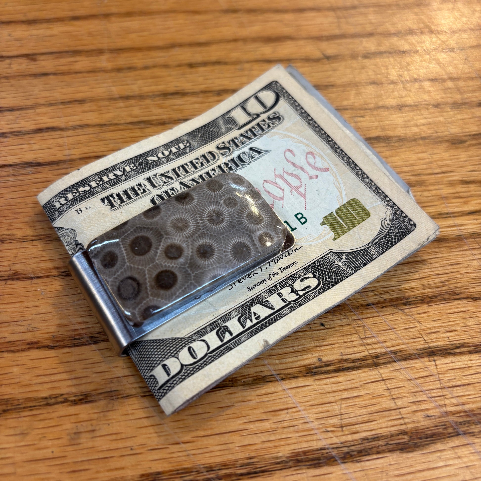 Money clip with petoskey stone on a ten dollar bill with a wooden surface background