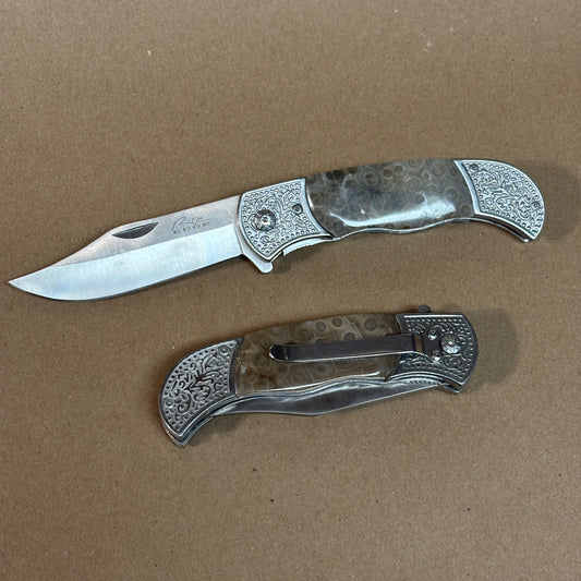 Two folding knives with decorative Petoskey stone handles on a brown background