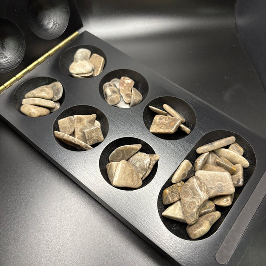 black wood mancala board with polished petoskey stone game pieces