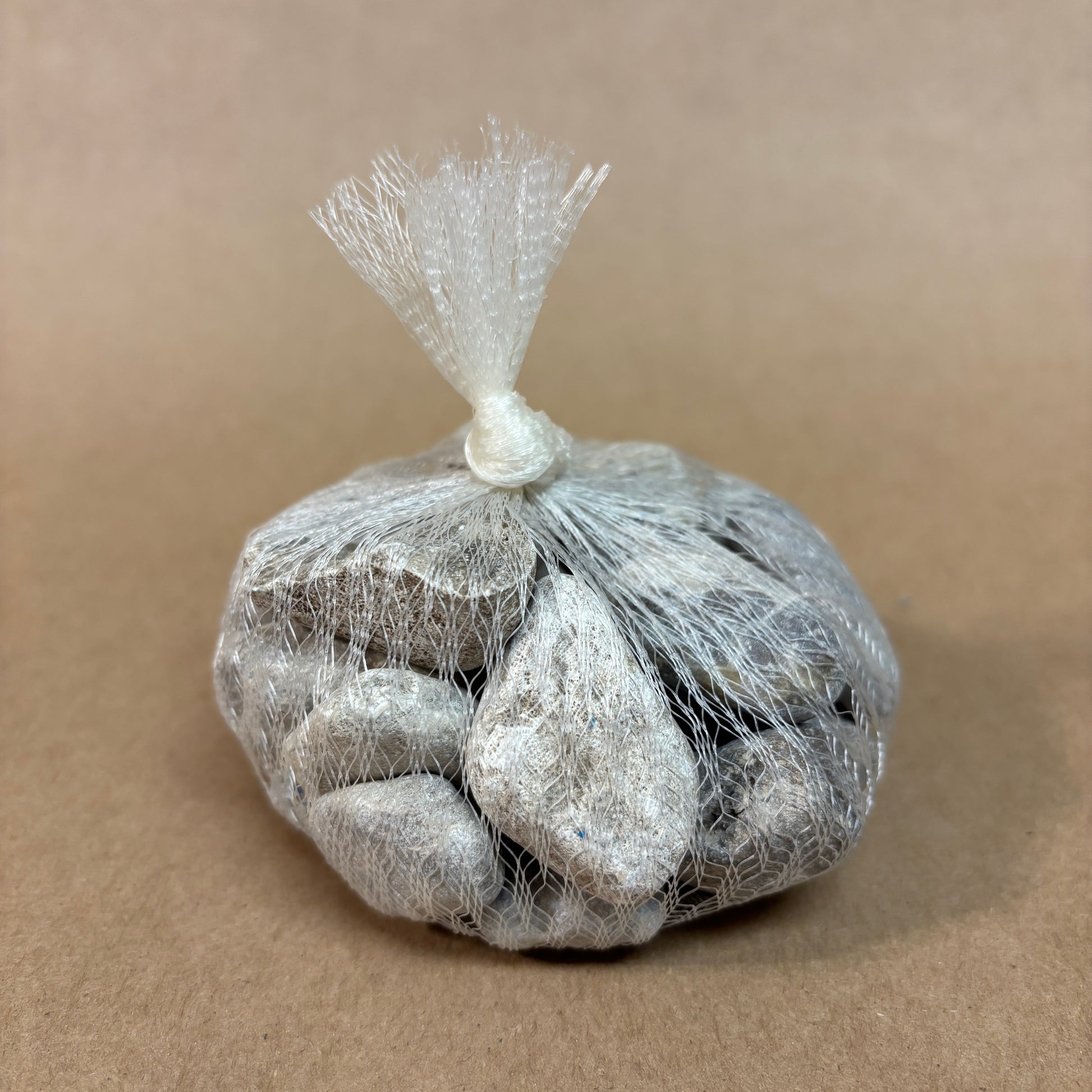 Bag of stones wrapped in netted bag on a beige background
