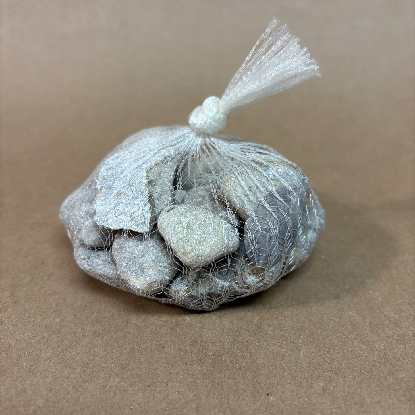 Bag of stones tied in a mesh bag on a brown background
