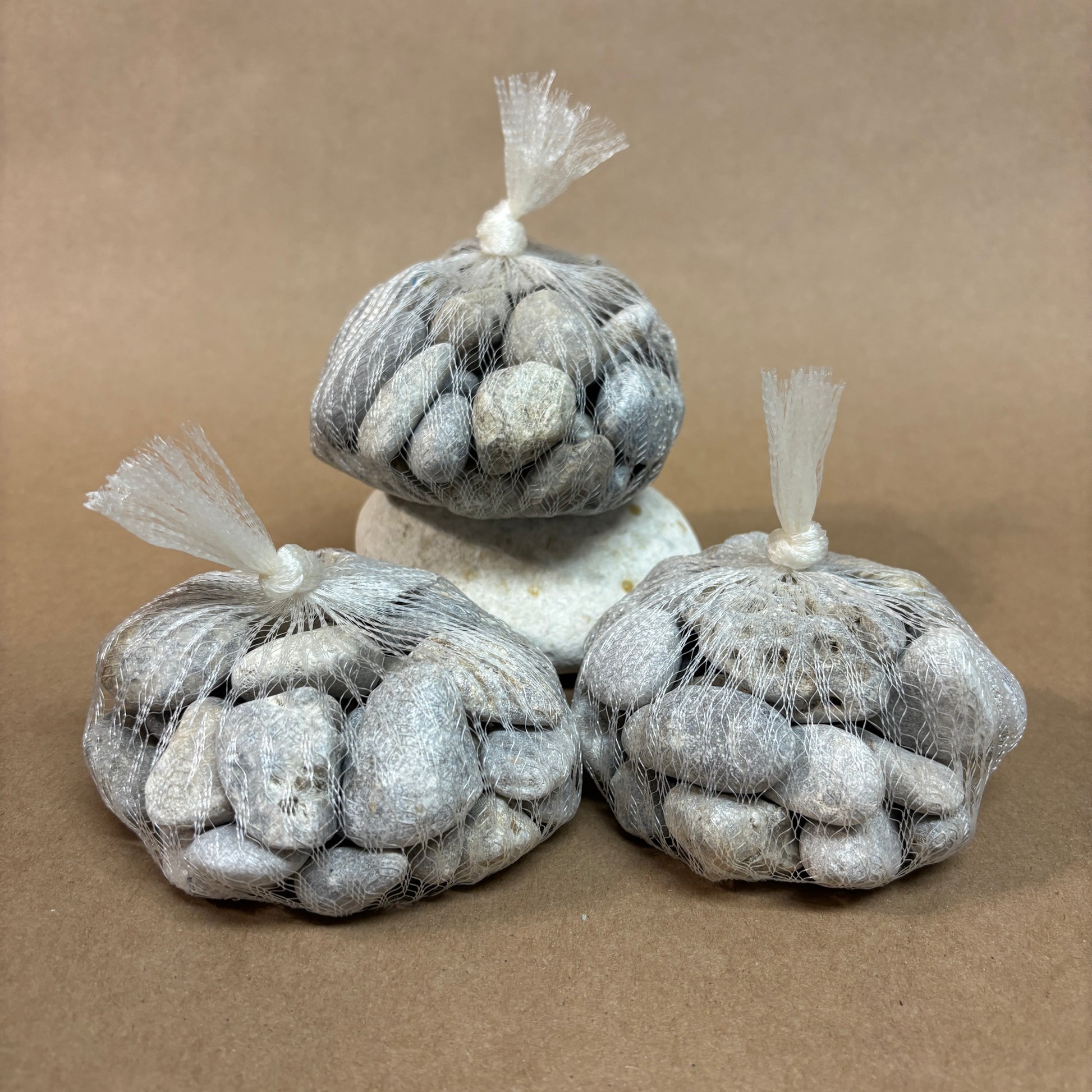 Three bags of stones in mesh bags on a brown background