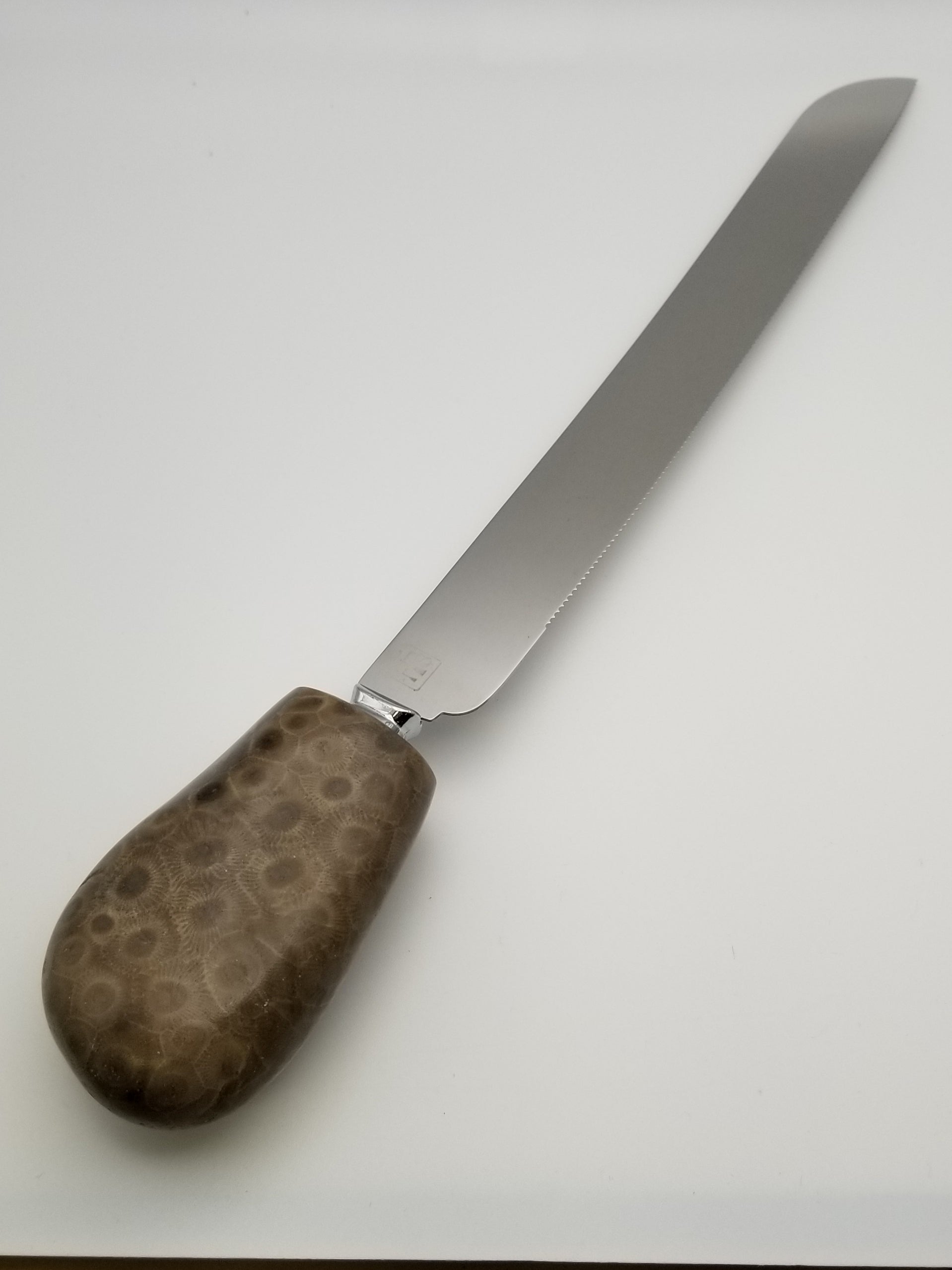 Serrated stainless steel kitchen knife with petoskey stone handle. Fully polished Petoskey stone handle.