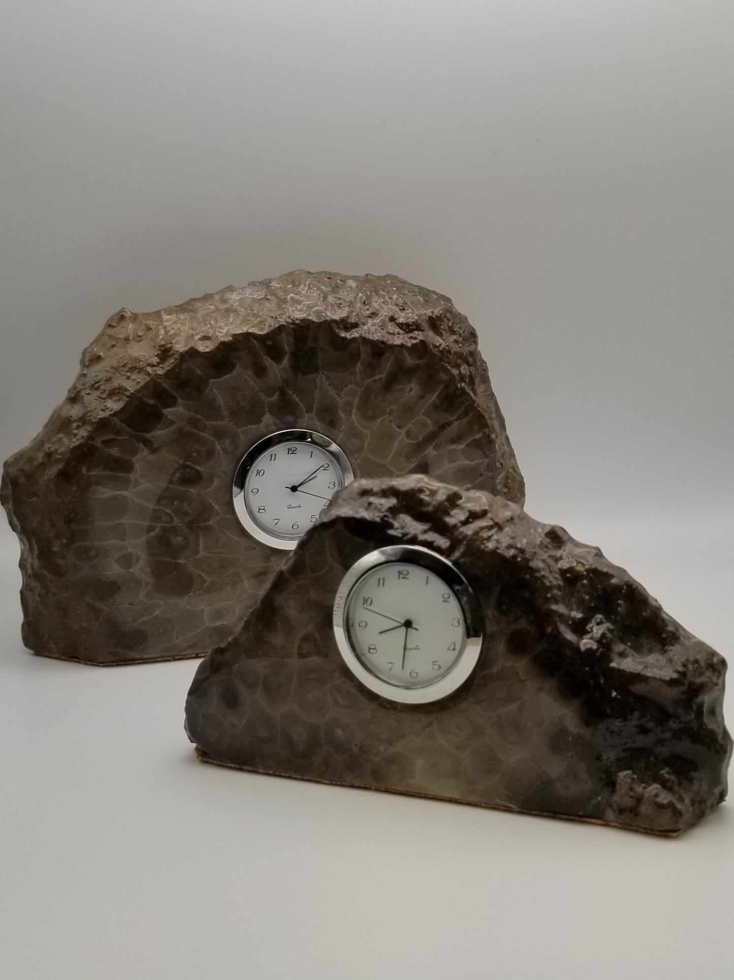 Two petoskey stone deck clocks in a size large and a size medium. Both have silver Quartz clock hardware. Clocks stone design is a very natural shape but into a thick slab.