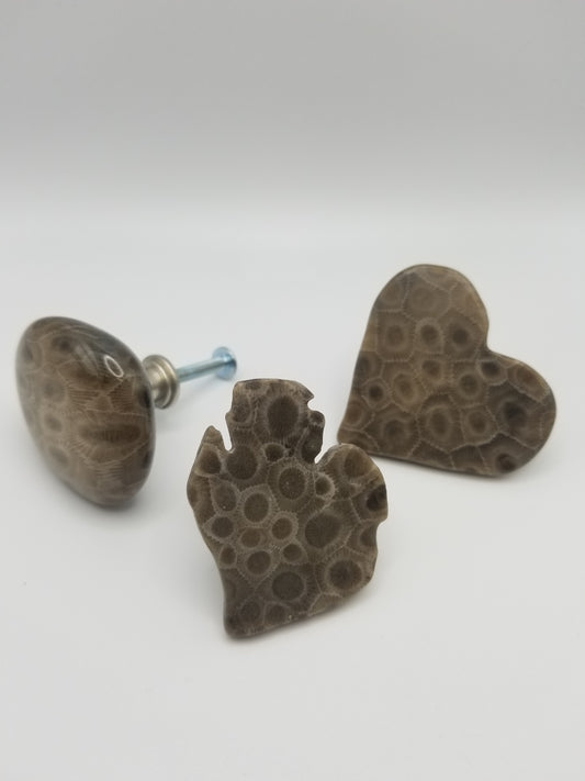 From left to right there is a classic polished rounded natural stone shaped knob, center is a lower michigan mitt shaped knob with intense pattern, and far right is a heart shaped knob with beautiful pattern and coloring. All three stone knobs are Petoskey stones.